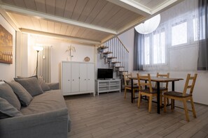 A modern living room with a sofa, TV, dining table, chairs, and a staircase. - Fiera Front Loft by Wonderful Italy (Bologna)