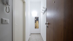 A hallway with a wooden door, a wall-mounted light fixture, a telephone, and a painting. - Caduti di Via Fani by Wonderful Italy (Bologna)