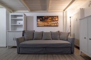 A neutral-toned room with a grey sofa, a white cabinet, and a wall-mounted picture of a historical building. - Fiera Front Loft by Wonderful Italy (Bologna)