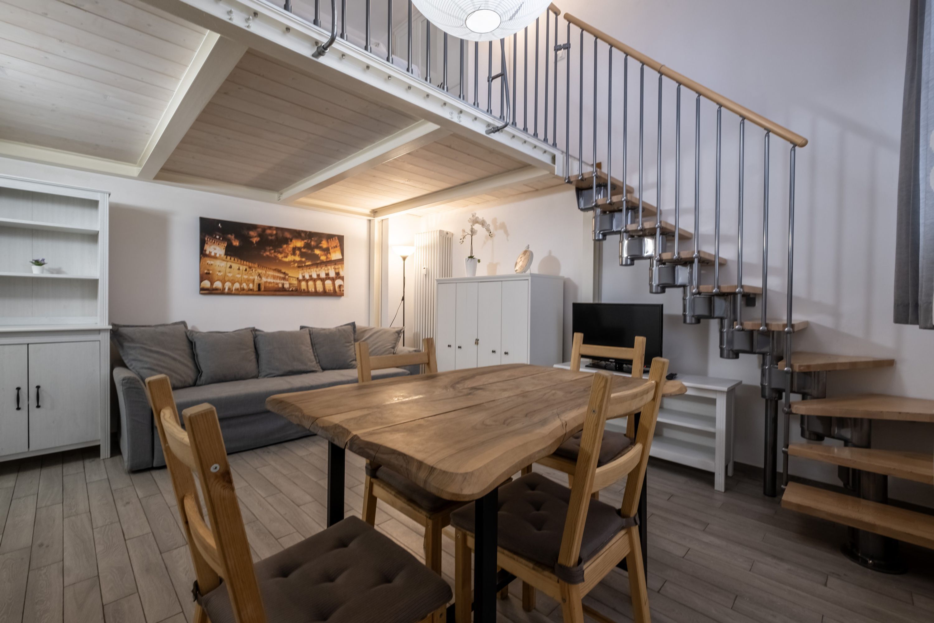Un interior moderno con comedor, sofá, escalera y obras de arte.