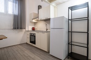 A compact kitchen with white cabinets, a built-in oven, a stainless steel range hood, and a white refrigerator. - Fiera Front Loft by Wonderful Italy (Bologna)