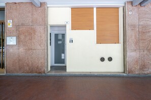 Ein Gebäudeeingang mit einer Tür, einem Wandsprechsystem und einem Brandmelder.