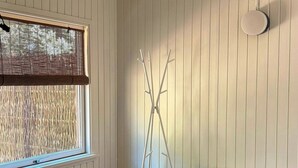 Huoneessa on sänky, lipasto, ikkuna, jossa on sälekaihtimet, jalusta ja kattotuuletin.