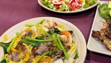 A table with various dishes, including a plate of stir-fried vegetables and meat, a salad, and a dish with grilled meat.