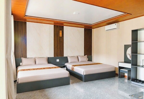 A modern hotel room with two beds, a desk, and a built-in wardrobe.