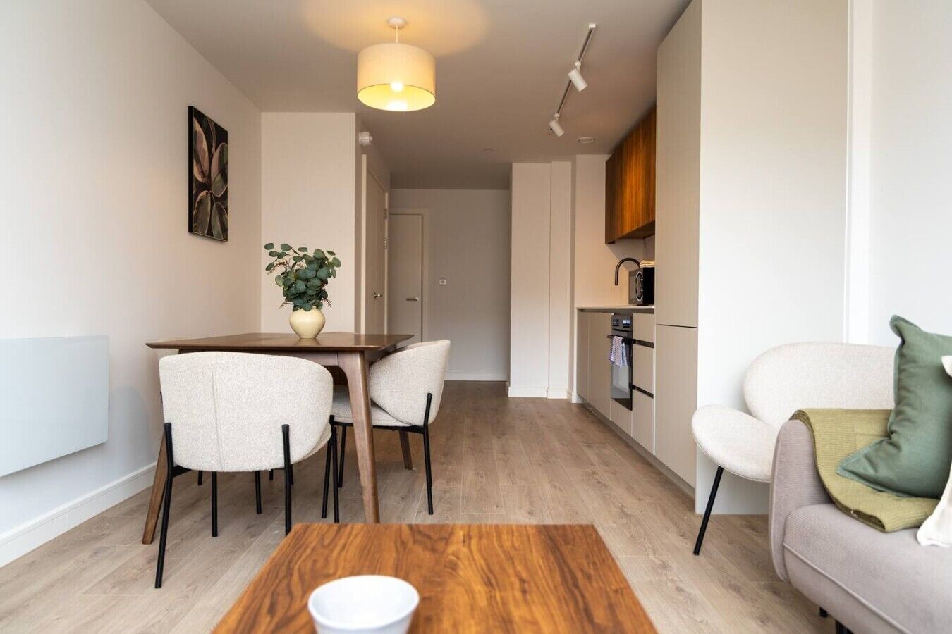 A modern apartment with a dining area, a kitchenette, and a living space.