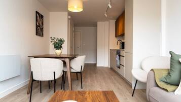 A modern apartment with a dining area, a kitchenette, and a living space.