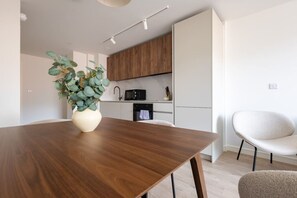 Cozinha moderna com área de refeições, um vaso com folhagem verde e uma cadeira branca.