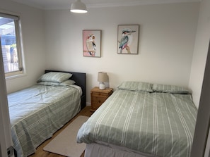 A bedroom with two single beds, a nightstand with a lamp, and two wall-mounted paintings of birds.