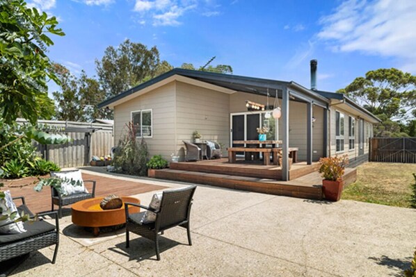 A single-story house with a patio area featuring outdoor furniture and a barbecue grill.