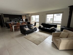 A spacious living area with a dining table, two sofas, and a kitchen in the background.