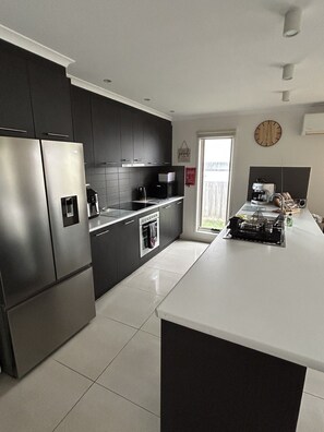 A modern kitchen with stainless steel appliances, a large island, and a view of the backyard.