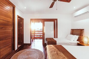 A bedroom with a wooden headboard, a bed with white bedding, a bedside table with a lamp, and a woven rug. - Deluxe Triple Suite at Villa Lux Do Mar (Jijoca de Jericoacoara)