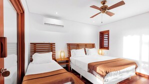 A hotel room with two beds, a ceiling fan, an air conditioning unit, and a window with blinds. - Deluxe Triple Suite at Villa Lux Do Mar (Jijoca de Jericoacoara)