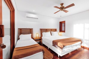 Ein Hotelzimmer mit zwei Betten, einem Deckenventilator, einer Klimaanlage und einem Fenster mit Jalousien.