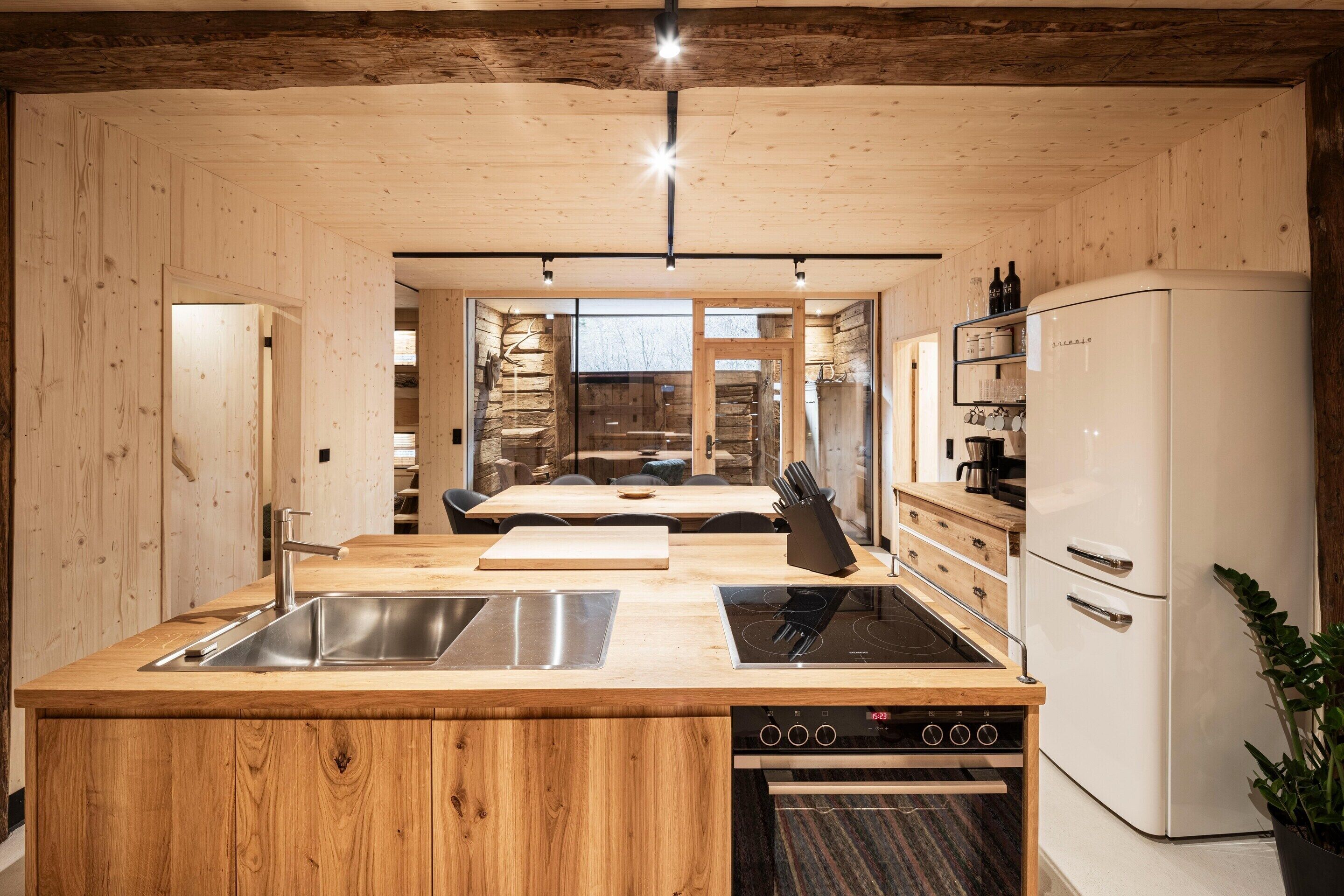 A modern kitchen with wooden walls, a built-in stove, and a refrigerator.