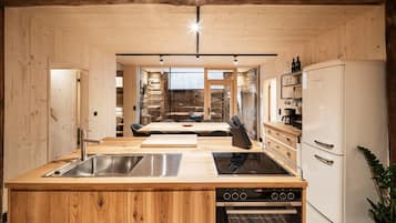 A modern kitchen with wooden walls, a built-in stove, and a refrigerator.
