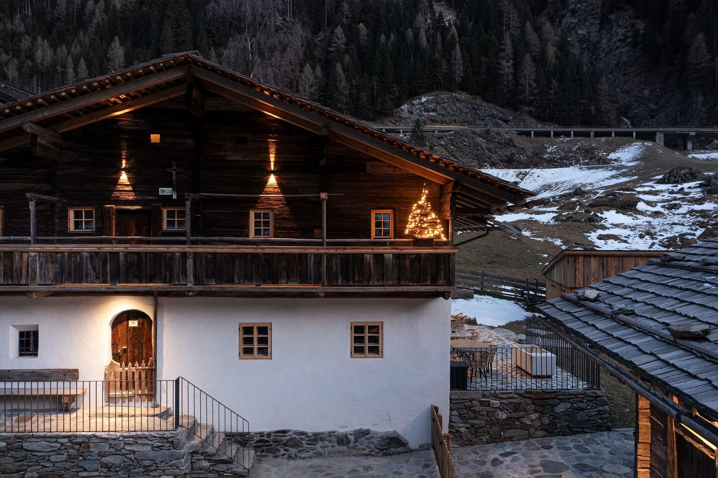 Eine zweistöckige Holzchalet mit Balkon, Stein Fundament und Blick auf einen verschneiten Berg.