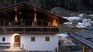 Eine zweistöckige Holzchalet mit Balkon, Stein Fundament und Blick auf einen verschneiten Berg.