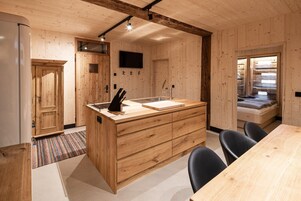 Un interior de madera con una cocina, una mesa de comedor y una cama.