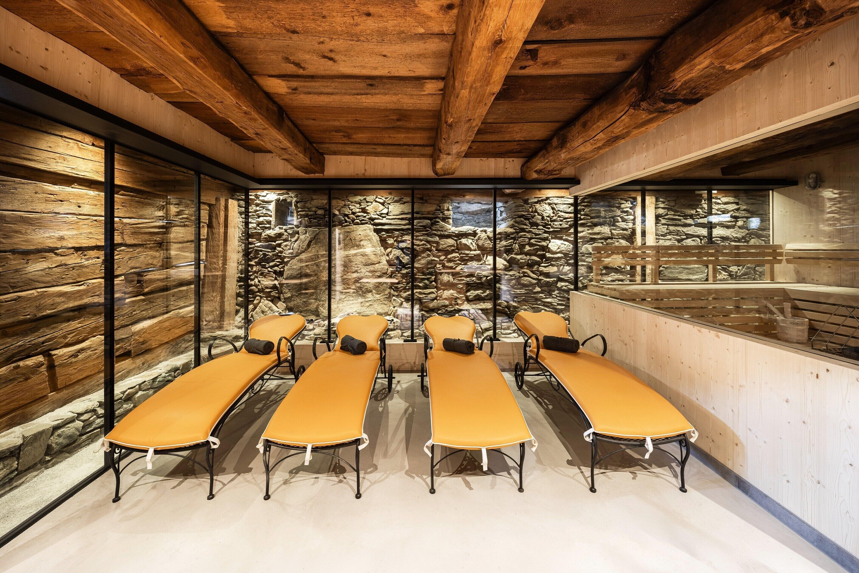 A room with wooden beams, stone walls, and a stone waterfall feature.