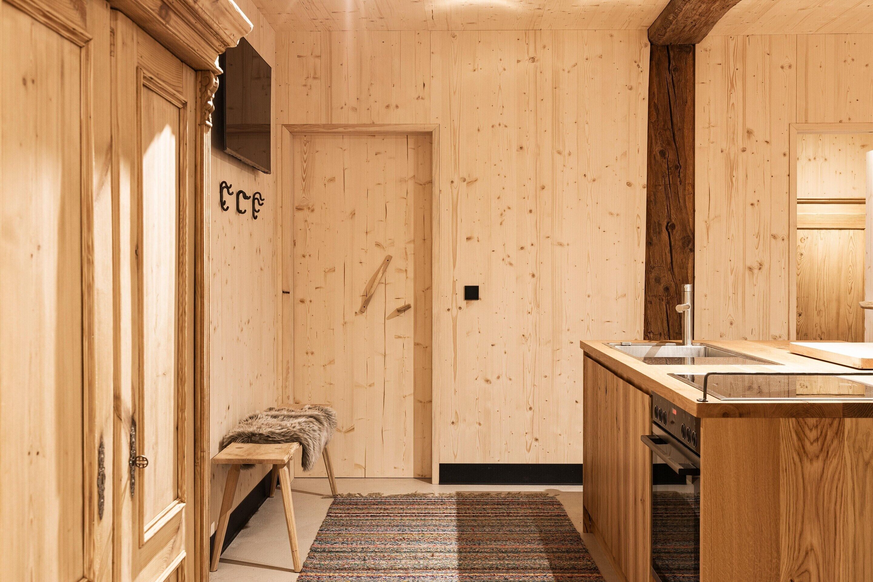 Un interior de madera con un banco, un lavamanos y una estufa.