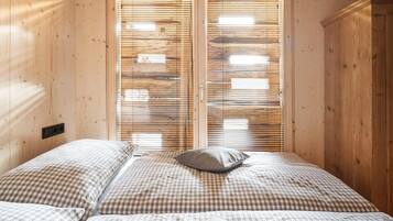 A bedroom with a checkered bedspread, a pillow, and wooden blinds.