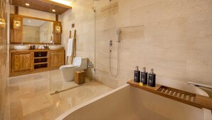 A modern bathroom with a glass-enclosed shower, a wooden vanity, a toilet, and a marble floor.