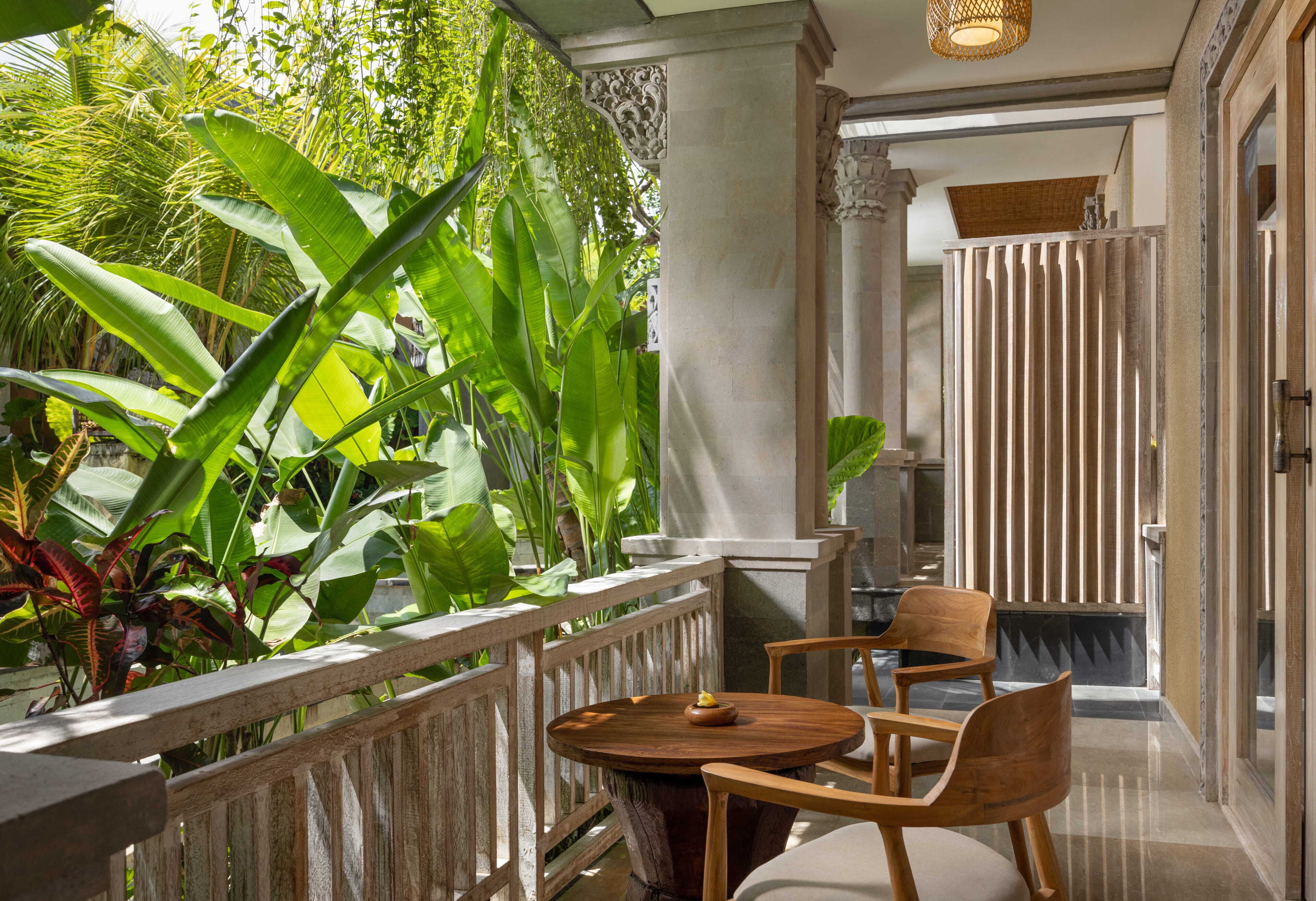 A wooden table and chairs in a room with a view of lush greenery.