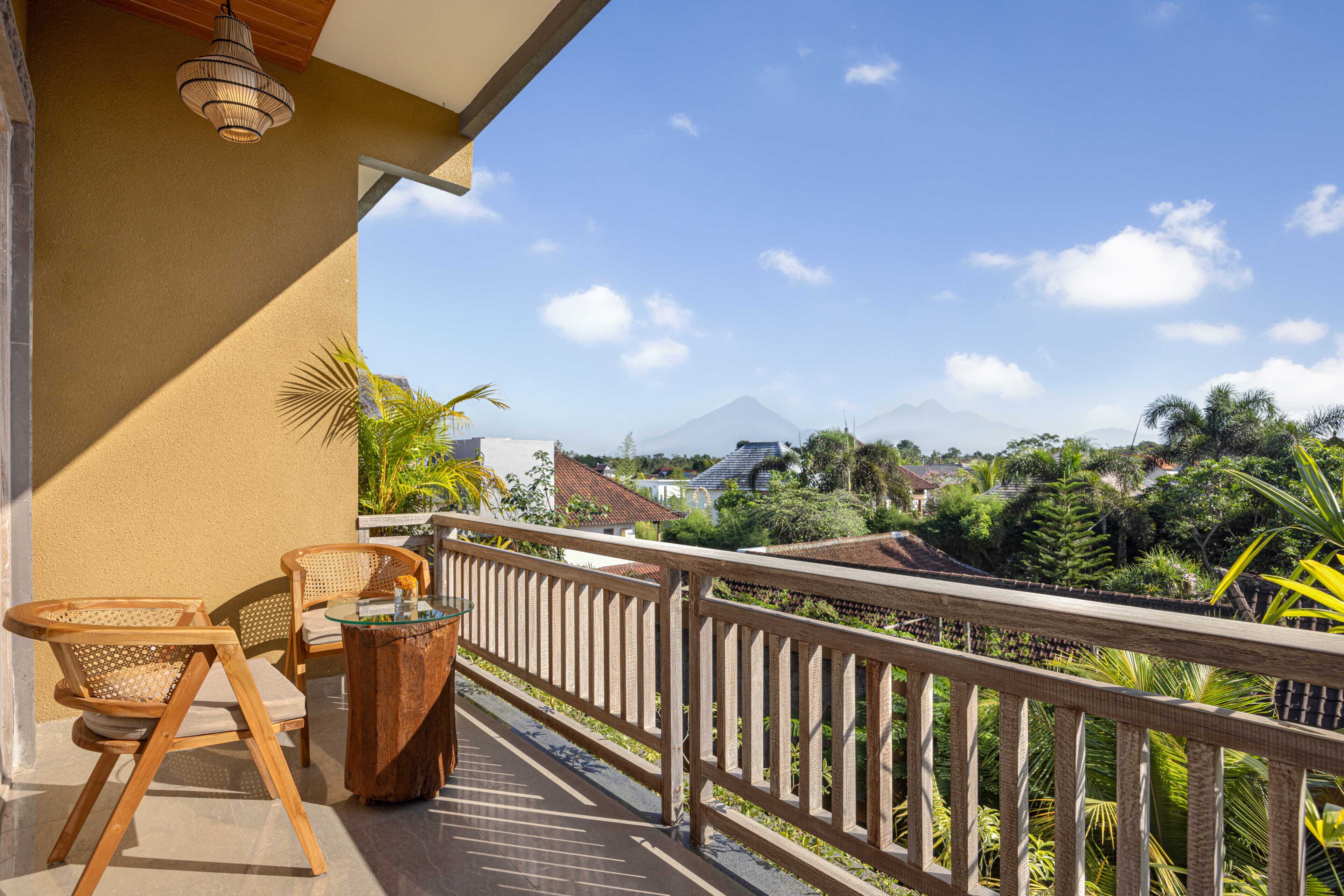 A balcony with a wooden railing, a table, and two chairs.