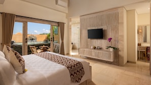 A hotel room with a large bed, a TV mounted on a wooden panel, and a view of the outdoors.