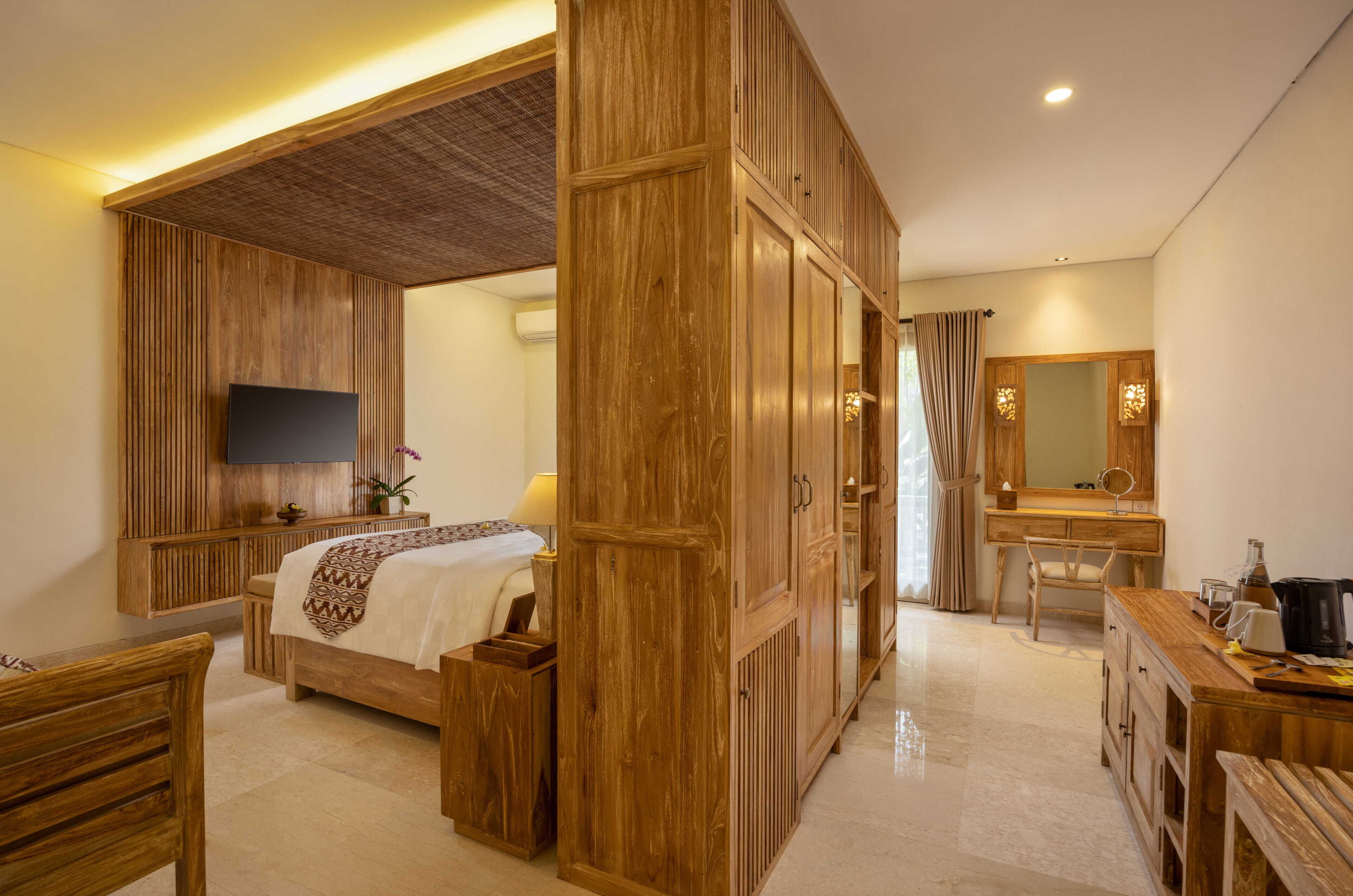 A hotel room with a bed, a desk, a chair, a television, and a bathroom with a mirror and sink.