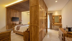 A hotel room with a bed, a desk, a chair, a television, and a bathroom with a mirror and sink.