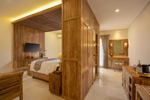 A hotel room with a bed, a desk, a chair, a television, and a bathroom with a mirror and sink.