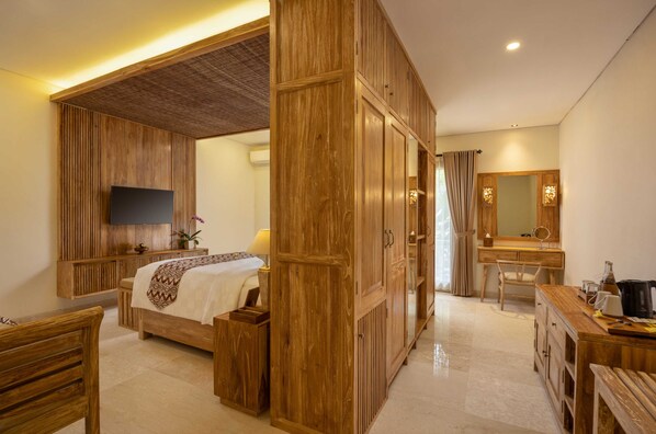 Une chambre d’hôtel comprenant un lit, un bureau, une chaise, une télévision et une salle de bain avec un miroir et un lavabo.