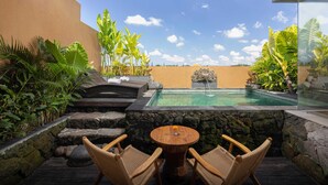A pool area with a stone wall, two wicker chairs, and a view of the sky.