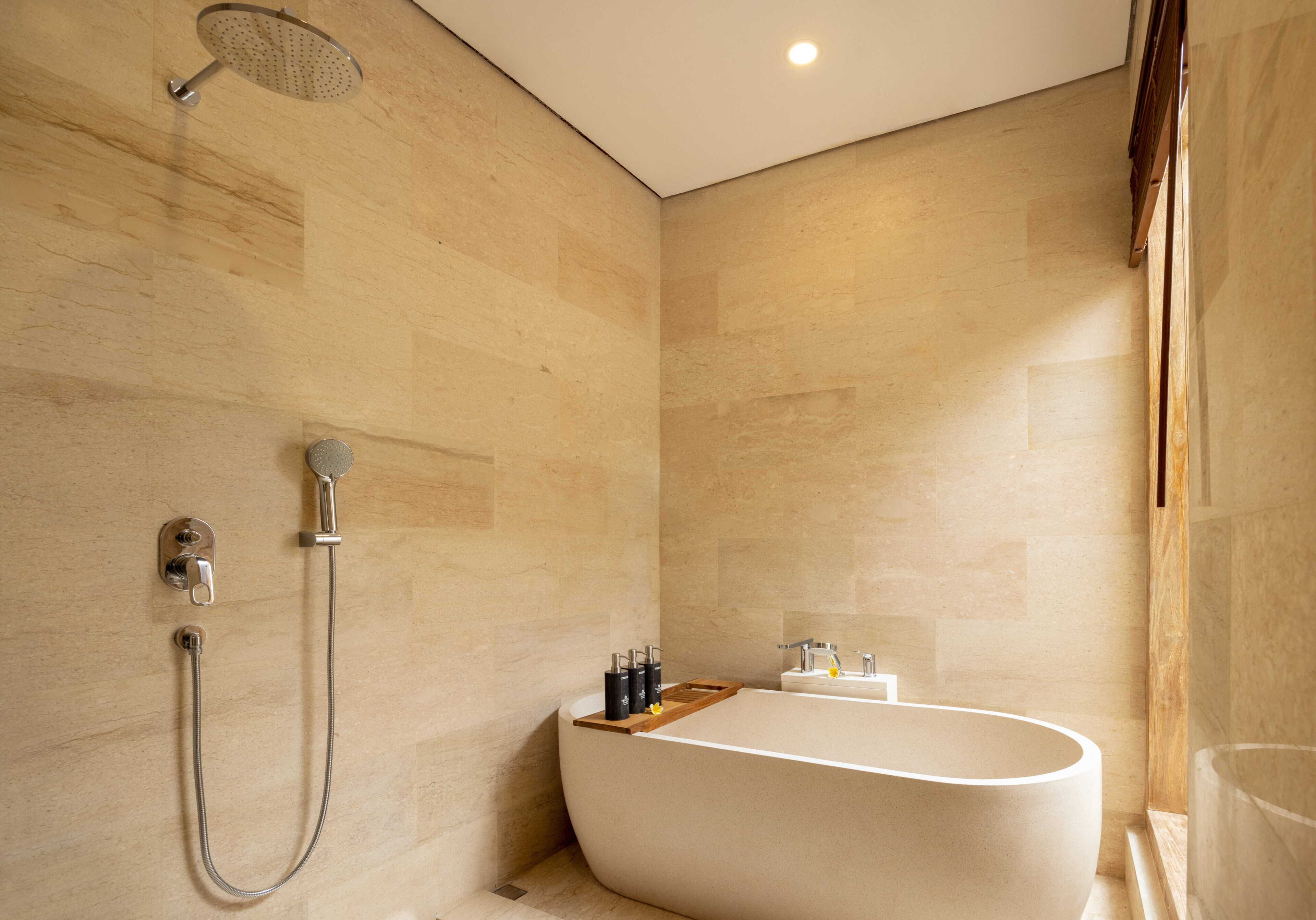 A modern bathroom with a freestanding bathtub, a handheld showerhead, and a wall-mounted faucet.