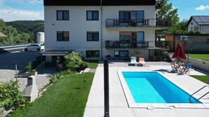A two-story house with a swimming pool, a balcony, and a garden.