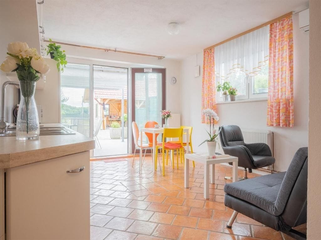 Um espaço de estar moderno com cozinha, mesa de jantar e cadeiras, sofá e porta de vidro deslizante para área externa.