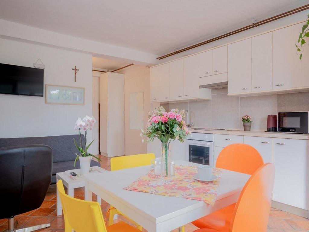 Un coin repas avec une table blanche, des chaises jaunes et un vase rempli de fleurs.