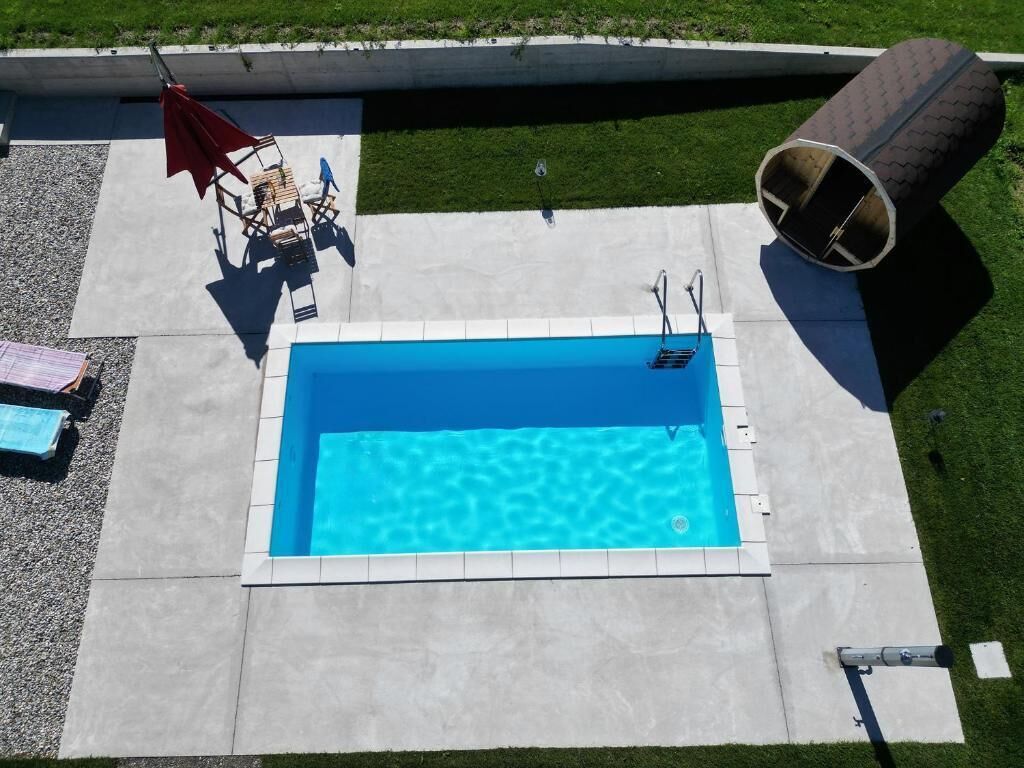 Una piscina rectangular con superficie azul cristalina, rodeada por una plataforma de concreto.