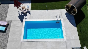 Una piscina rectangular con superficie azul cristalina, rodeada por una plataforma de concreto.