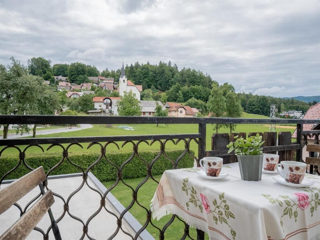 A balcony with a table set for two, overlooking a village with houses and a church.