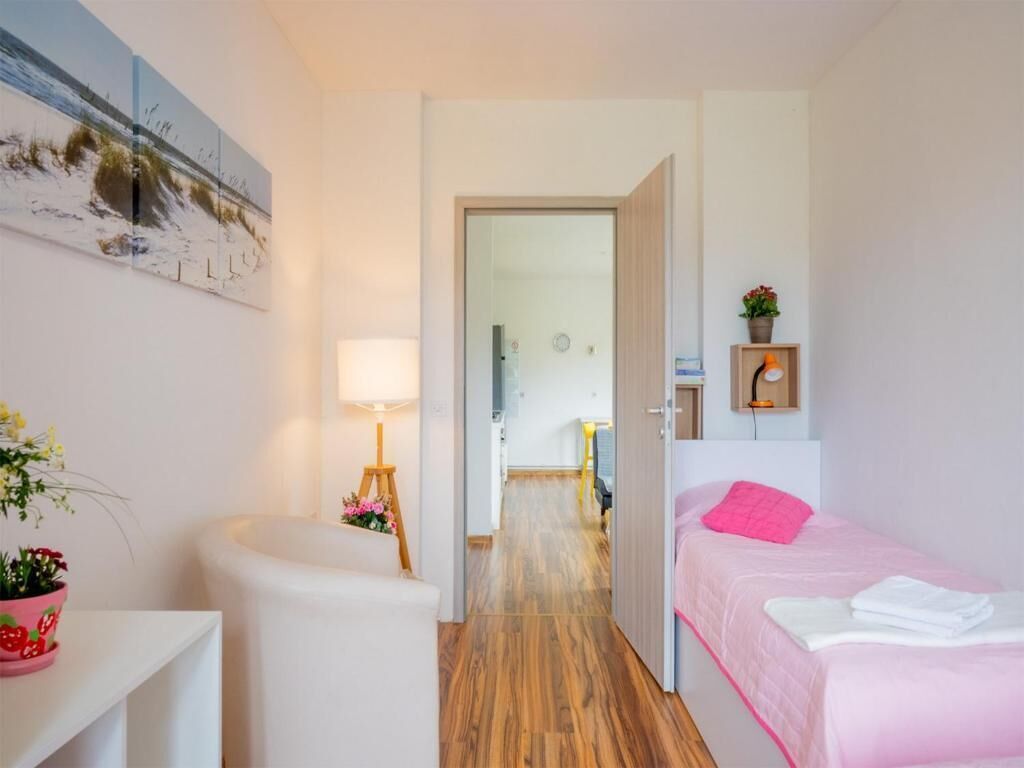A bedroom with a bed, a bedside table, a lamp, and a wall-mounted painting.
