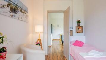 A bedroom with a bed, a bedside table, a lamp, and a wall-mounted painting.