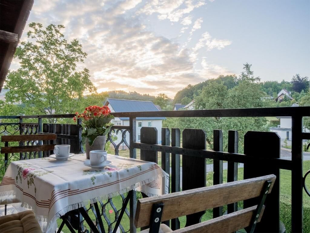 Un balcón con una mesa para dos, una banca y vistas a una zona residencial.