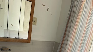 A bathroom with a sink, mirror, toilet, and a striped shower curtain.