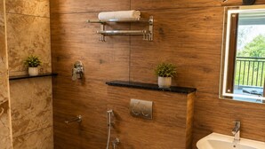A modern bathroom with a wooden wall, a toilet, a bidet, a sink, and a small window. - Foggy Woods Resort Wayanad (Vythiri)