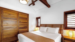 A bedroom with a wooden bed, a nightstand with a lamp, and a wardrobe. - Deluxe King Suite at Villa Lux Do Mar (Jijoca de Jericoacoara)