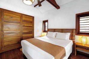 A bedroom with a wooden bed, a nightstand with a lamp, and a wardrobe. - Deluxe King Suite at Villa Lux Do Mar (Jijoca de Jericoacoara)